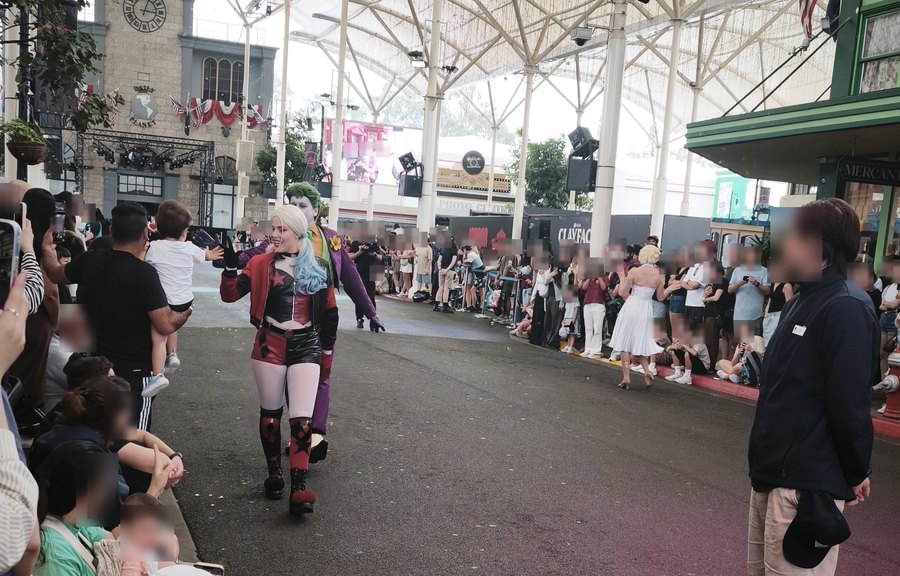 Harley Quinn and the Joker waving to the crowd during the Movie World Hero Parade