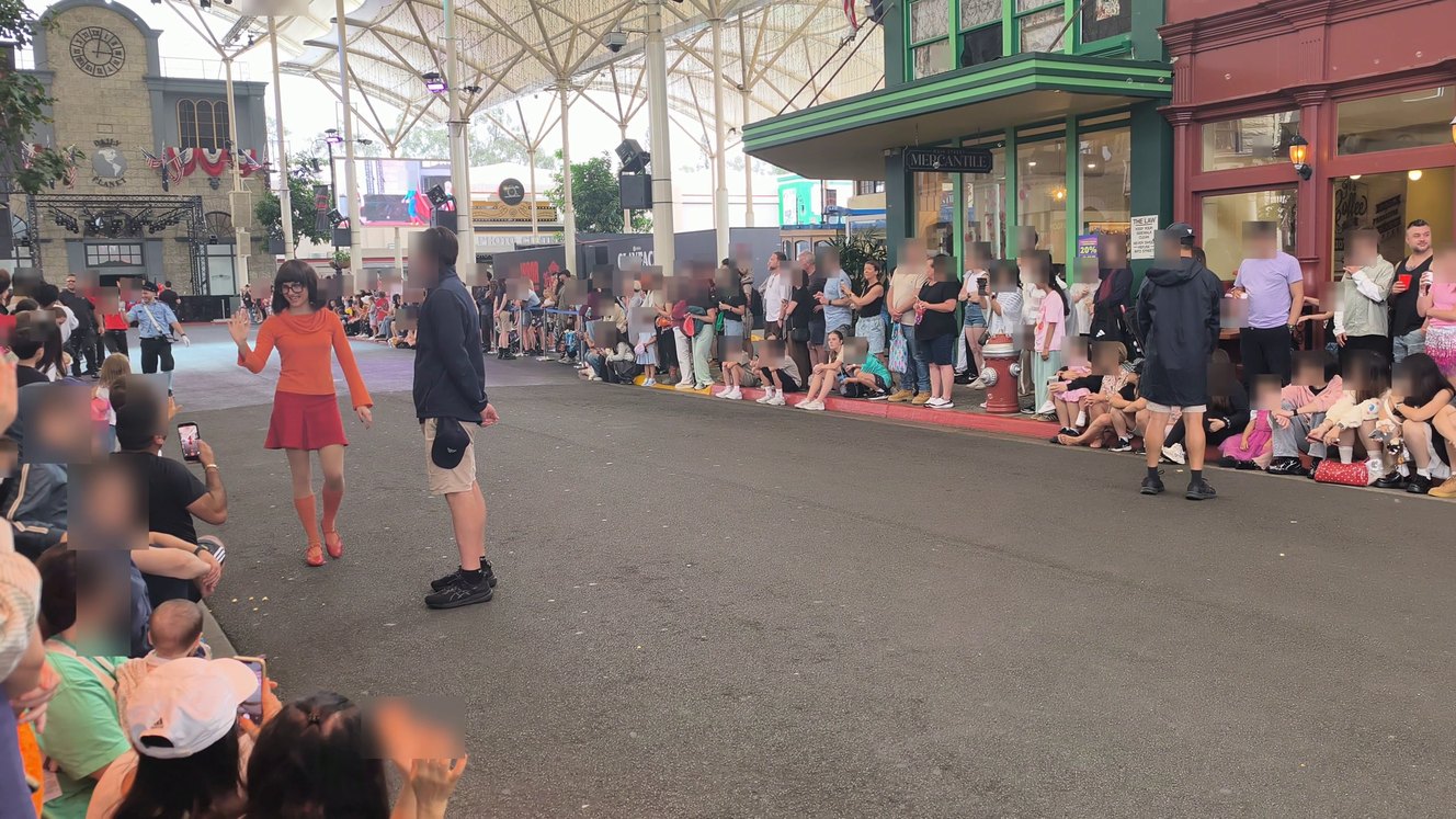 Velma from Scooby-Doo dancing along Main Street at Movie World with crowds lining both sides